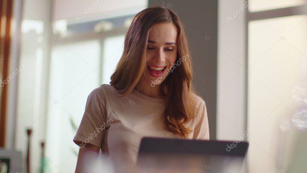 Businesswoman receiving good news on laptop. Lady eating corn flakes on kitchen