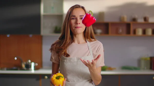 Kvinnan kastar paprika på köket. Hemmafru tittar på kameran hemma — Stockfoto