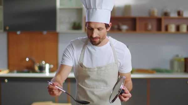 Chef cooking soup on stove. Smiling man preparing dinner at home — Φωτογραφία Αρχείου