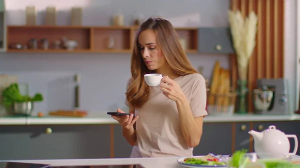 Woman taking selfie on smartphone at kitchen. Lady drinking coffee in morning — Stockfoto
