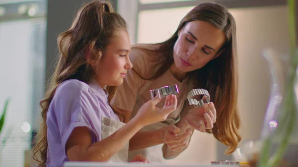 Улыбающаяся женщина и девушка используют кусачки для печенья на современной кухне — стоковое фото