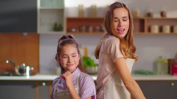 Happy daughter and mother dancing back to back on kitchen in slow motion — Zdjęcie stockowe