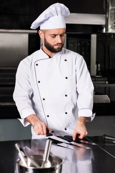 Chefe macho no restaurante da cozinha. Profissional masculino concentrado com facas . — Fotografia de Stock