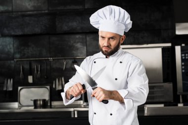 Lokanta mutfağında erkek aşçı. Çapraz bıçaklı profesyonel portresi.