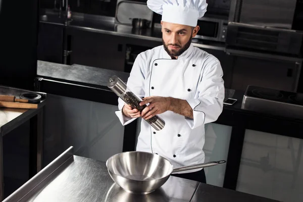 Chef masculin avec wok au restaurant de la cuisine. Homme concentré avec poivre. — Photo