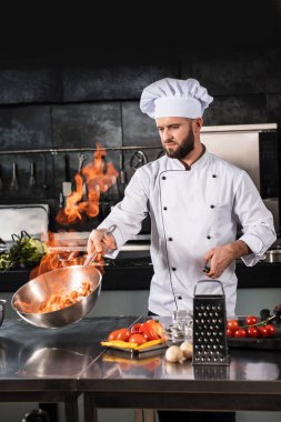 Şef mutfak restoranında ateşle yemek hazırla. Mutfakta tavalı şef..