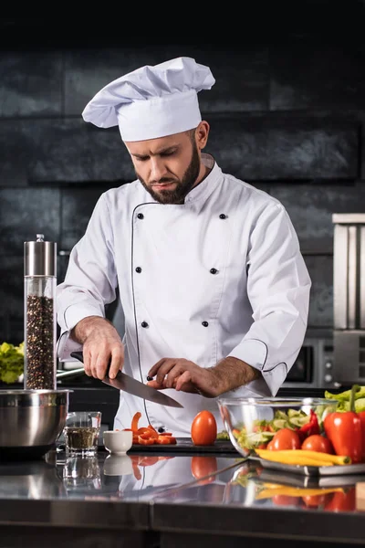 Szef kuchni z nożem w restauracji. mężczyzna profesjonalny cięcie pomidor. — Zdjęcie stockowe