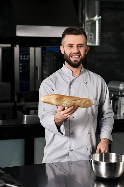 Szef kuchni z chlebem w kuchni. Szczęśliwy profesjonalista z francuskim chlebem. — Zdjęcie stockowe