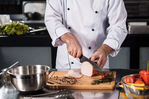 Chef mãos com faca fatia de carne na cozinha. Closeup chef mãos cortando zumbido . — Fotografia de Stock