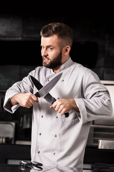 Séf bácsi keresztbe tett késekkel a konyhában. Férfi séf keresztbe tett késekkel. — Stock Fotó