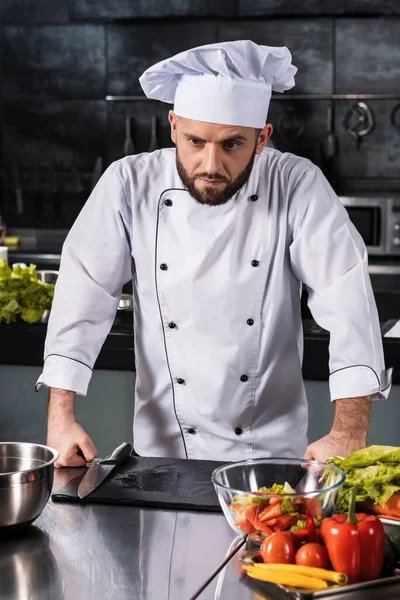 Chef male at kitchen restaurant. Portrait of serious male cooker in uniform.