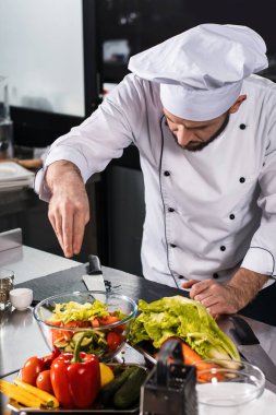 Şef mutfak restoranında sebze pişirir. Şef erkek tuzlu taze yemek.
