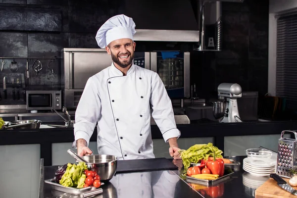 Chefe com vegetais crus na cozinha. Profissional feliz preparar alimentos frescos . — Fotografia de Stock