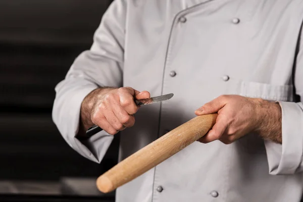 Chef hands with roller. Closeup male hands with wooden roller and knife.