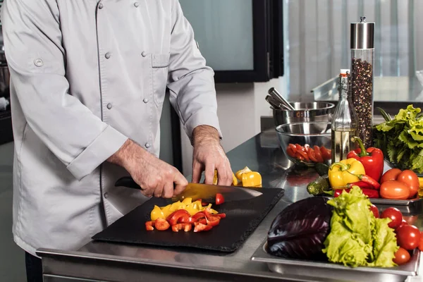 Ręce szefa kuchni kroją jedzenie w kuchni. Szef kuchni z bliska kroić pieprz z nożem. — Zdjęcie stockowe
