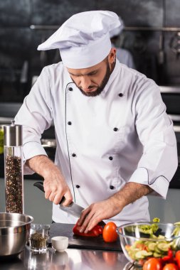 Restoran mutfağında bıçaklı aşçı erkek. Profesyonel şef domates kesiyor..