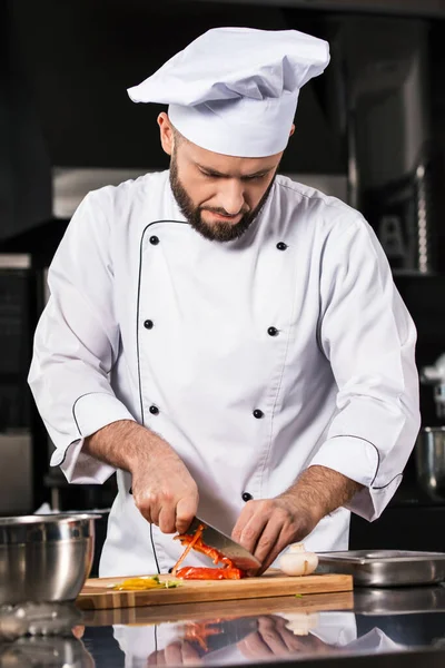 Chef homem com faca na cozinha do restaurante. Chef macho cortando pimenta . — Fotografia de Stock