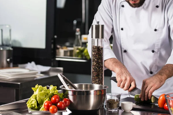 Mãos masculinas a cortar comida à mesa da cozinha. Closeup chef mãos cortar legumes . — Fotografia de Stock