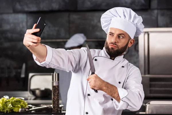 Επαγγελματίας σεφ κάνει φωτογραφία. Πορτρέτο του αρσενικού σεφ με μαχαίρι λήψη selfie. — Φωτογραφία Αρχείου