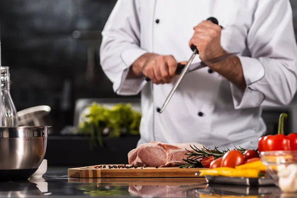 Chef hands with knife and meat at kitchen. Closeup chef hands with knife.