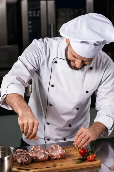 Homem chef cozinhar bife no restaurante da cozinha. Chef em carne de sal uniforme . — Fotografia de Stock