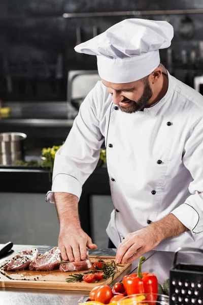 Chef macho preparar carne na cozinha. Happy chef cozinhar bife no restaurante da cozinha . — Fotografia de Stock