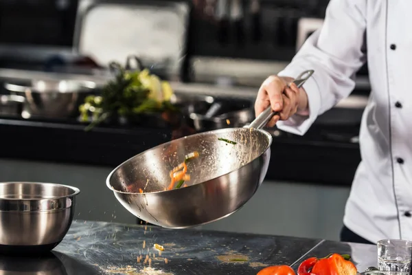 Chef mão manter wok. Mãos fechadas jogando comida na cozinha profissional . — Fotografia de Stock