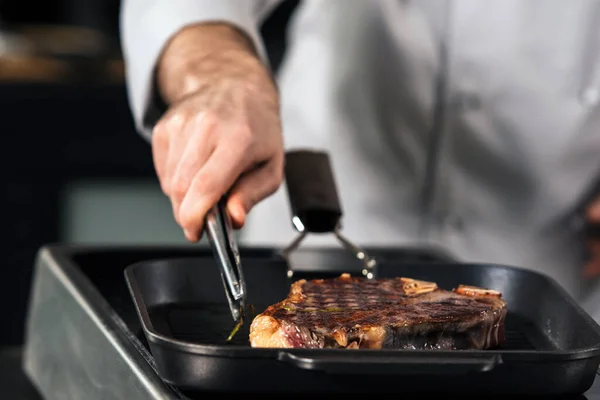 Chef man cook steak on griddle pan. Closeup chef hand prepare grill beef.