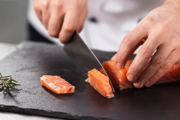 Chef cut salmon fillet. Closeup chef hands slice fresh fish.