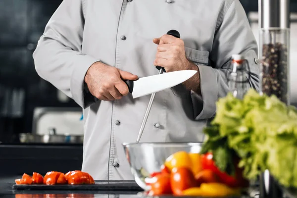 Chef homem afiar faca no restaurante da cozinha. Masculino profissional afiar faca . — Fotografia de Stock