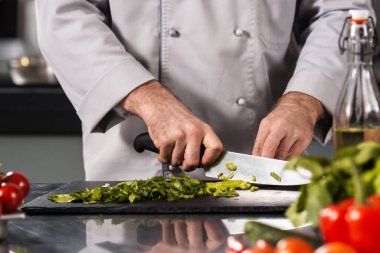 Erkek elleri mutfakta yemek keser. Yakından aşçı elleri bıçakla sebze kesiyor..