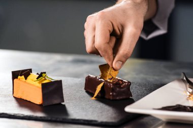 Şefin elleri tatlıyı süslüyor. Kapalı eller pastayı çikolatayla süslüyor..