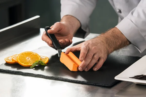 Chef cozinhar bolo de laranja no restaurante da cozinha. Closeup chef mãos bolo de decoração . — Fotografia de Stock