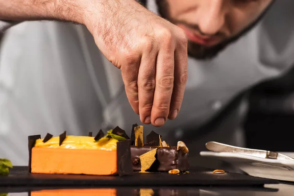 Kokken pynter desserten på kjøkkenet. Closeup hånd dekorere kake med sjokolade. – stockfoto