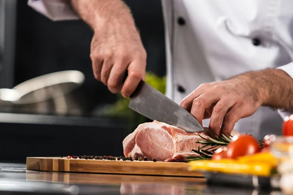 Chef mãos com faca cortar carne na cozinha. Closeup chef homem mãos cortadas carne . — Fotografia de Stock