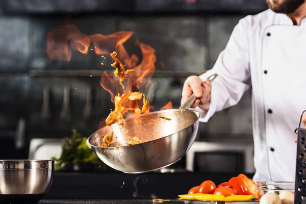 Kokki kädet pitää wok tulella. Lähikuva kokki kädet kokki ruokaa tulella. kuvapankin valokuva