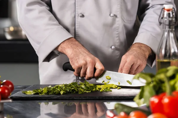 Menschenhände schneiden Essen in der Küche. Großaufnahme Koch gibt Schneiden von Gemüse mit Messer. Stockbild