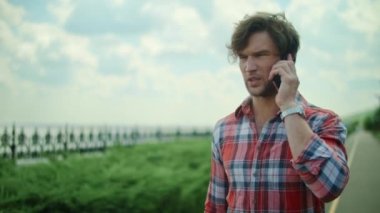 Parkta akıllı telefondan konuşan bir adam. Telefonu olan adam yolda yürüyor.