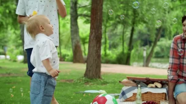 Gülümseyen baba parkta çocuklara bakıyor. Aile hafta sonunu birlikte geçiriyoruz. — Stok video