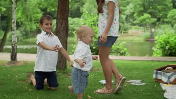 Felices hermanos jugando en el parque. Familia joven teniendo picnic al aire libre . — Vídeo de stock