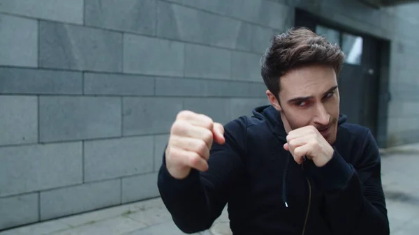 Fokuserad man utbildning boxning punch på stadens gata. ung man boxning utomhus — Stockfoto