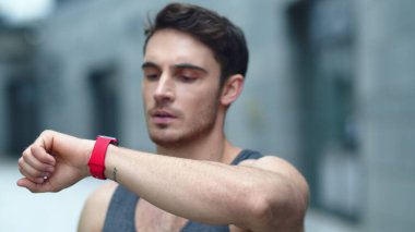 Closeup male athlete using smart clock outside. Fit man setting smart watch clipart