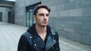 Yakından vahşi adam caddede yürüyor. Gri duvar arkaplanında hareket eden yakışıklı adam