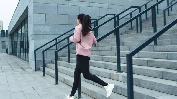 Fitness nainen koulutus ajaa liikuntaa portaissa. Urheilullinen tyttö juoksee alas portaita — kuvapankkivalokuva