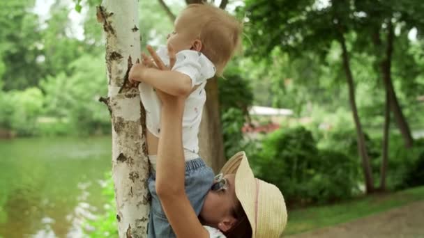 Sestra drží malého bratra venku za ruce. Rodinný čas strávený v parku — Stock video