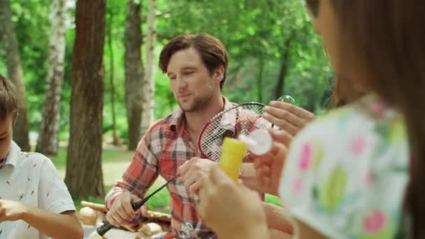 Die Familie vergnügt sich gemeinsam im Park. Glückliche Geschwister spielen mit Seifenblasen — Stockvideo