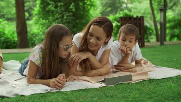 Madre con bambini che guardano lo schermo del tablet nel parco. Famiglia utilizzando pad esterno — Video Stock