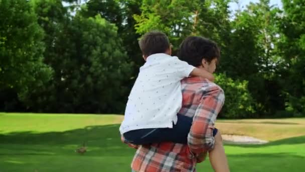 Le père tourne dans le parc avec son fils à l'arrière. Famille drôle s'amuser à l'extérieur — Video