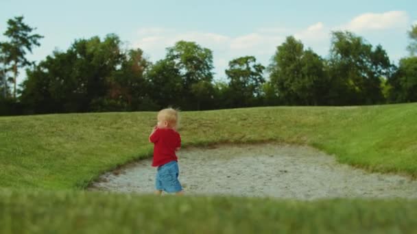 Мальчик ходит по зеленому полю. Веселый ребенок держит мяч в руках на открытом воздухе — стоковое видео