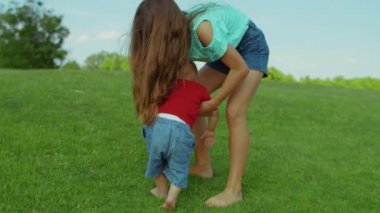 Kardeşimin yerden kalkmasına yardım eden abla. Bebek kucağında bir kız.